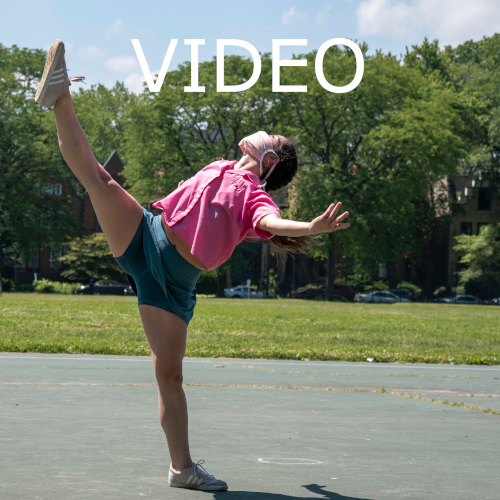 Text: Video - a white woman with brown hair in blue shorts and a pink top stands outdoors on one leg kicking the other very high while leaning back and looking at the sky