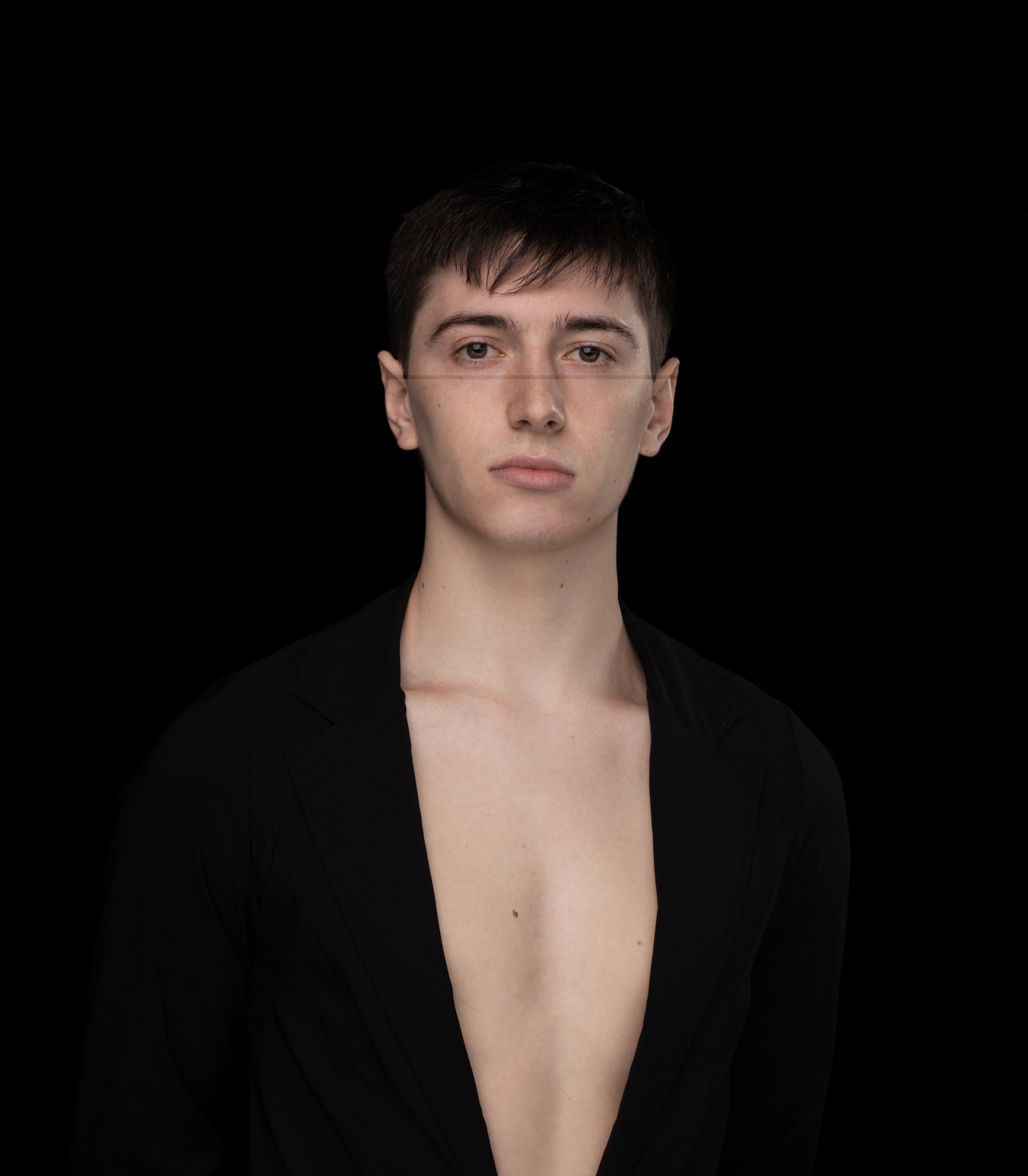 headshot of Reid - a young man with short dark hair, fair skin, and brown eyes in front of a black background