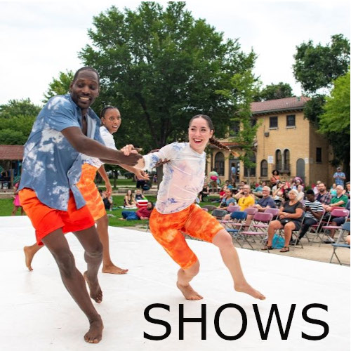 Text: Shows - 3 dancers in white, blue, and orange costumes runningon an outdoor stage in front of a large audience