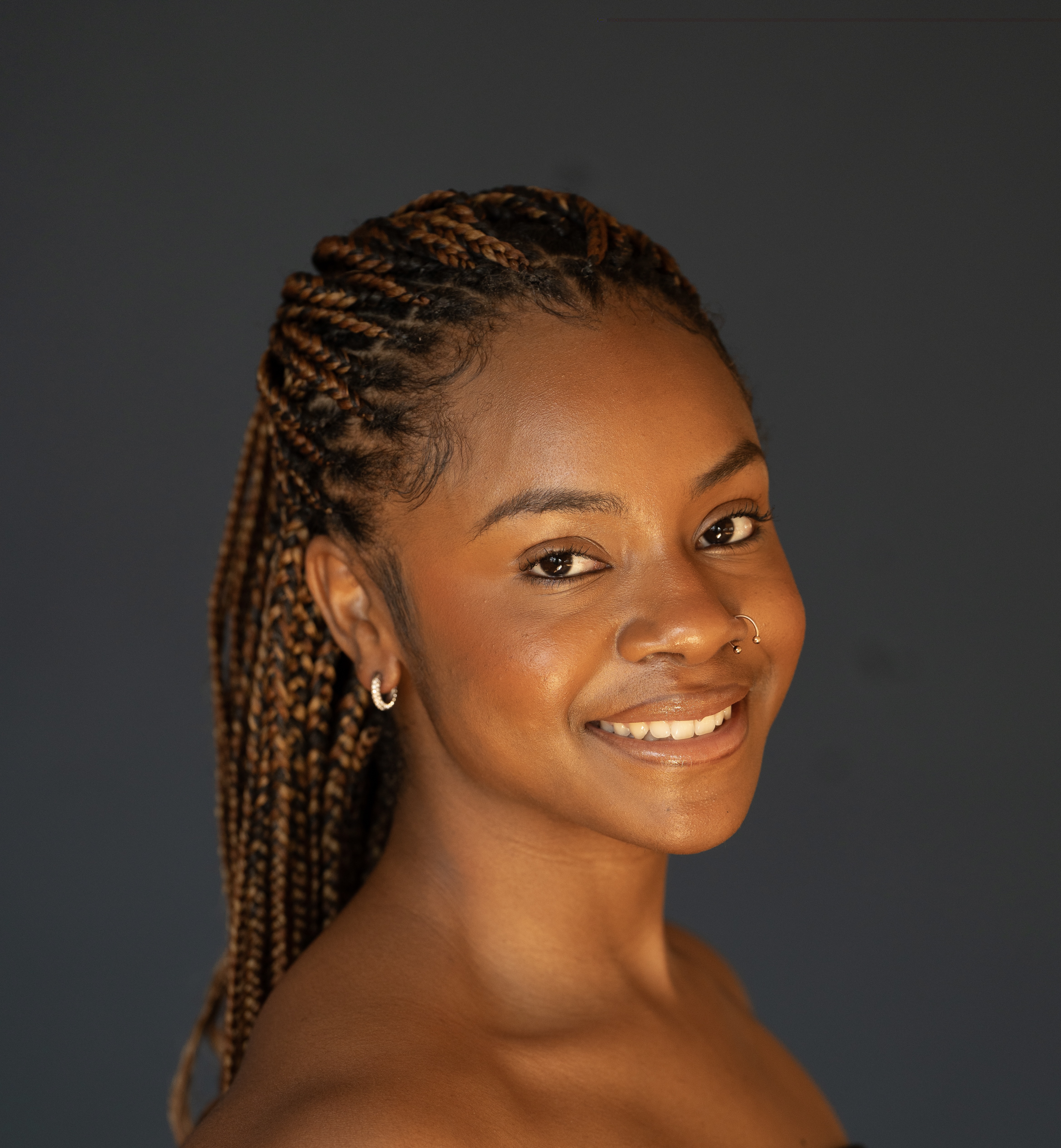 Headshot of Ashley, an African American woman with dark brown hair in braids and brown eyes.